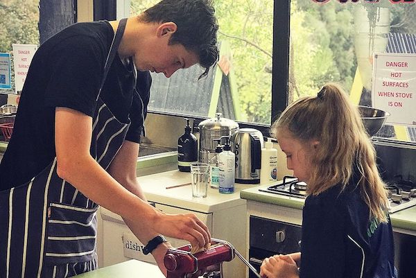 Older child demonstrating in kitchen with younger child