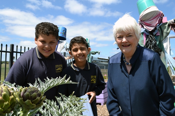 Two students with Stephanie Alexander in a garden with scarecrow behind Two students with Stephanie Alexander in a garden with scarecrow behind