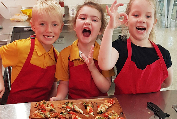 Three children making happy faces over slices of pizza Three children making happy faces over slices of pizza