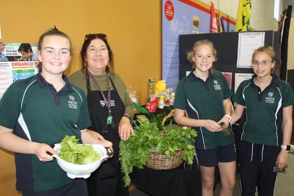 Students and teacher holding baskets of produce, indoors