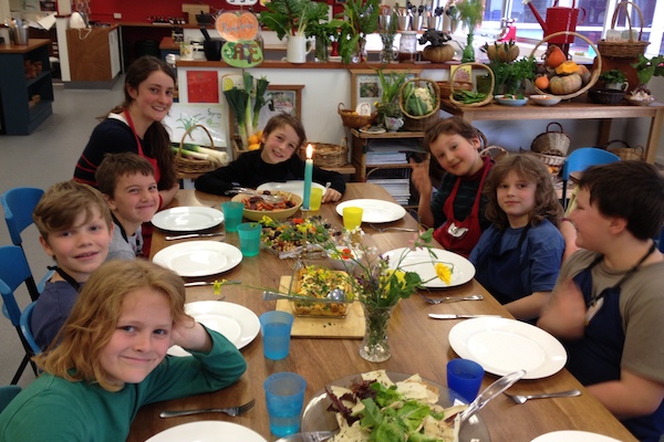 Children and educator gathered around a set table