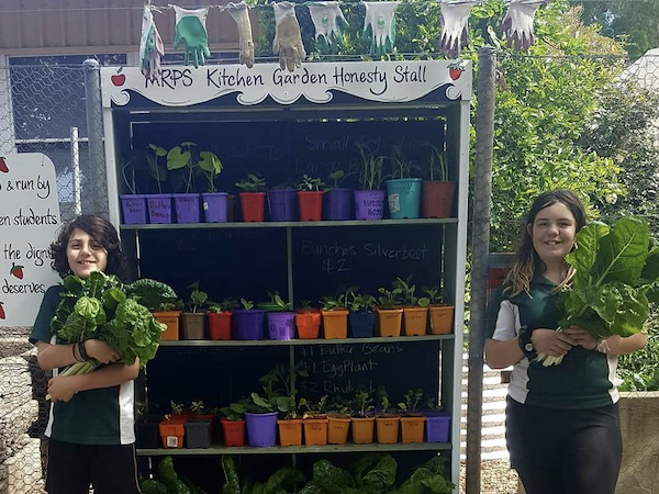 Two children either side of a produce stall Two children either side of a produce stall