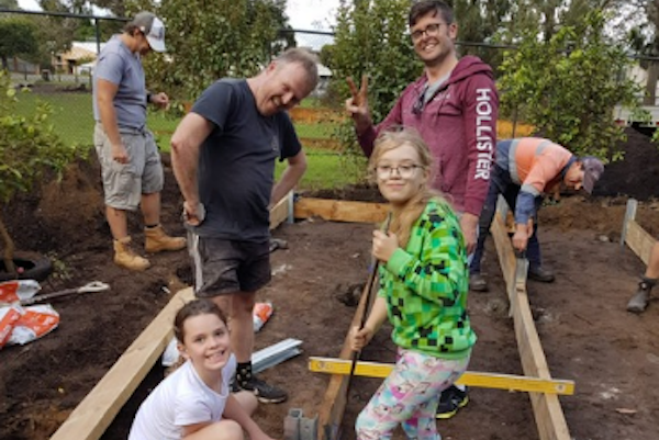 Adults and students constructing garden beds