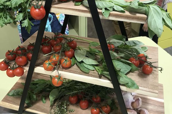 Wooden a-frame shelves filled with basil, tomatoes and garlic