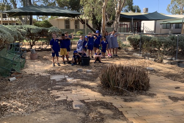 Kids in desolate garden space pulling faces and with thumbs down