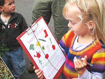 Young female student holding a clipboard containing a worksheet about food education.