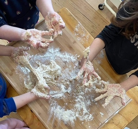 Three children, visible from above stretching out dough. Three children, visible from above stretching out dough.