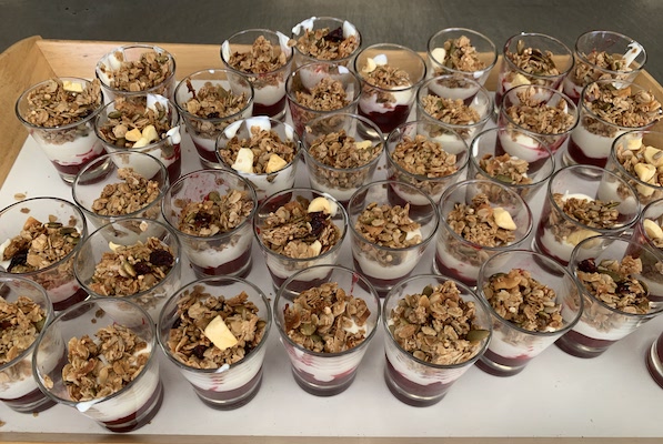 Many glasses with yoghurt and granola on a bench
