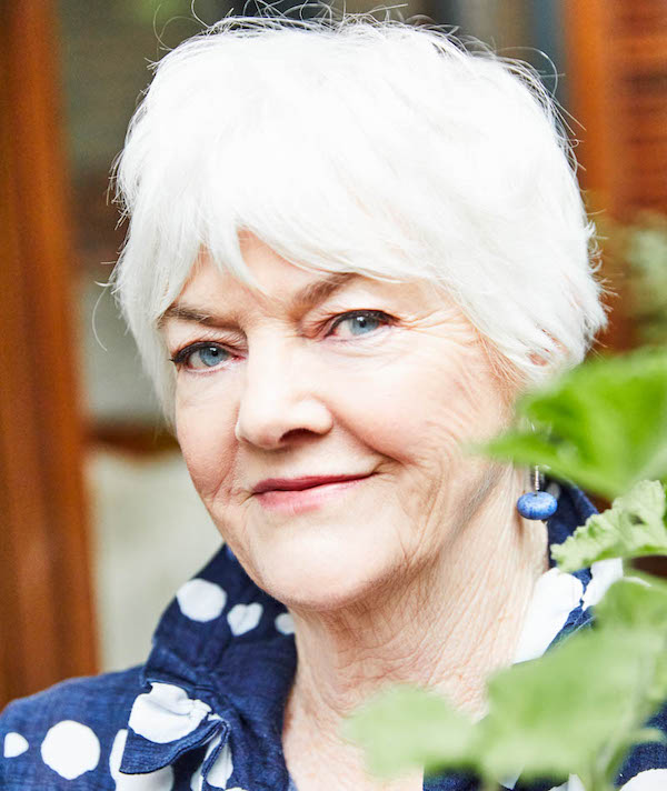 Headshot of woman with grey-white hair, wearing blue and white shirt