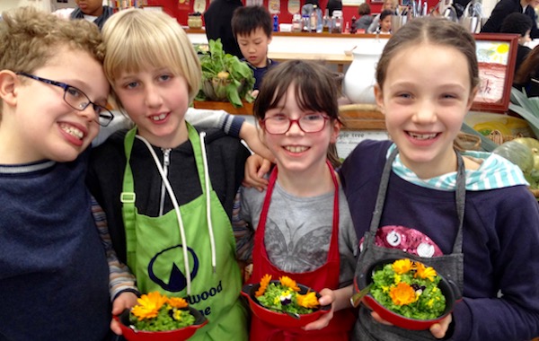 Children standing together holding small salad bowls