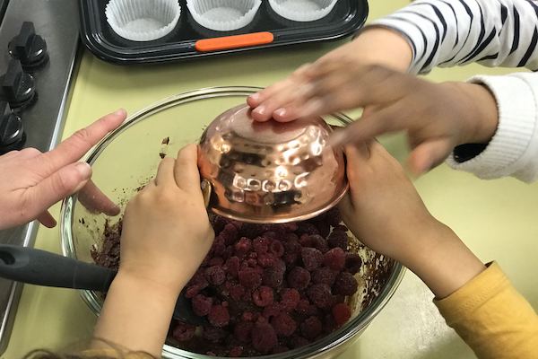 Berries in a bowl, surrounded by small hands